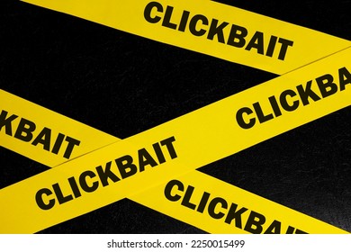 Clickbait scam alert, caution and warning concept. Yellow barricade tape with word clickbait in dark black background. - Shutterstock ID 2250015499