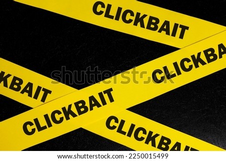 Clickbait scam alert, caution and warning concept. Yellow barricade tape with word clickbait in dark black background.
