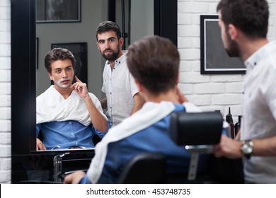 The client and barber look in the mirror and choose the design of the beard