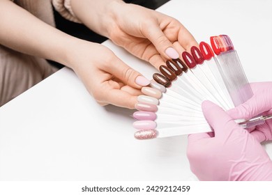 Client choosing color for gel nail polish application in the salon. View from a side, close up - Powered by Shutterstock