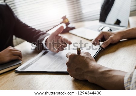 client customer signing contract and discussing business with legal consultants, notary or justice lawyer with laptop computer and wooden judge gavel on desk in courtroom office, legal service concept