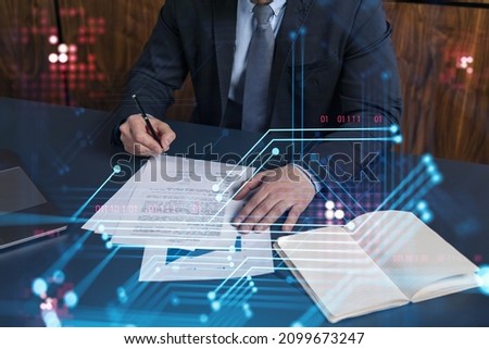 A client in dark blue suit is signing a contract to create a new software to present it in start up conference and gain investments to create a product. Technological graph over the desk.