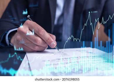 A client in formal wear is signing the contract to invest money in stock market. Internet trading and wealth management concept. Forex and financial hologram chart over the desk.