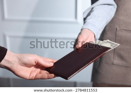 Client giving bill presenter with tips to waiter in restaurant, closeup. Space for text