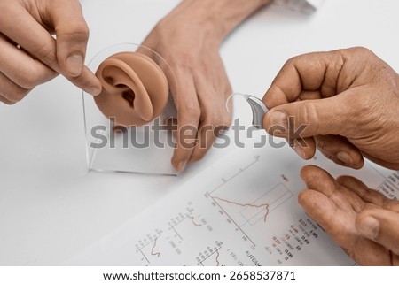 Client learns about hearing aids while examining ear anatomy with a professional at an audiologist office. Hearing solutions