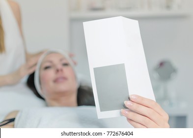 Client lying in ordination and showing to the camera white paper with empty space for text. - Powered by Shutterstock