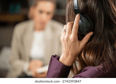 Client receiving EMDR therapy with alternating auditory stimulation through headphones under therapist guidance. Highlights bilateral processing and structured trauma-focused treatment.