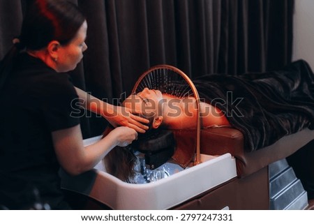 Client receiving a head spa treatment with water jets and scalp massage, promoting relaxation and hair care in a salon. Japanese spa head