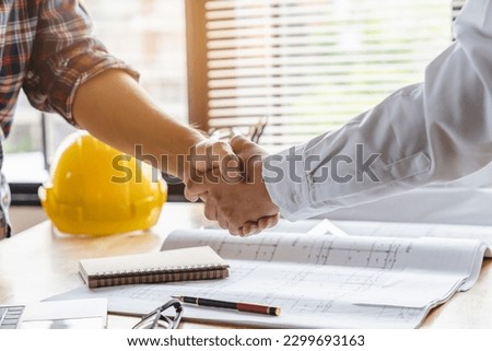 Client shaking hands with contractor after confirm blueprint to renovate house.