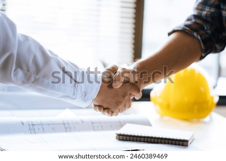Client shaking hands with contractor after confirm blueprint to renovate house.