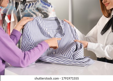 Client showing blouse to worker at dry-cleaner's, closeup