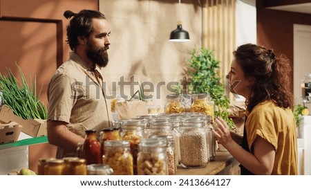 Client talking with seller in eco friendly shop, inquiring about food items ethical sourcing. Green living man in local store chatting with storekeeper about bulk products