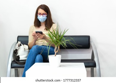 Client In The Waiting Room With Mask And Looking At The Mobile