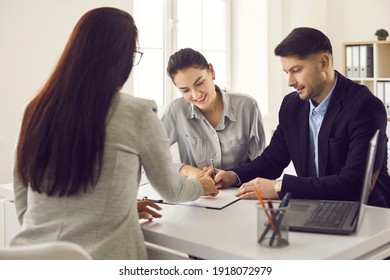 Clients Signing Paper Documents. Young Family Meeting Bank Manager, Loan Broker, Or Real Estate Expert. Happy Married Couple Putting Signature On Rental, Lease, Mortgage Or House Purchase Agreement