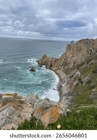 Cliff coastline with ocean waves and dramatic cloudy sky
