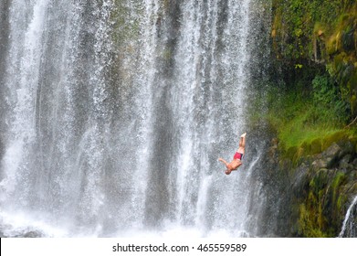 Cliff Diver With Waterfall In Background, Unrecognized And Unknown Person