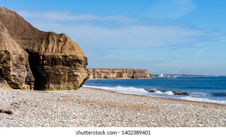 Cliff face with a large cave embedded within at Seaham Hall Beach, County Durham, Tyne and Wear, England UK. North East coastline in the background with the North Sea to the right.