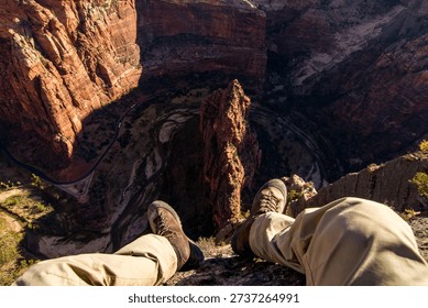 Cliffside perspective looking down toward the canyon floor in Zion National Park, Utah, showing height, exposure and the winding route below.