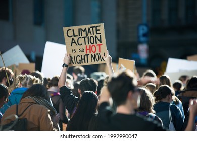 "Climate Action is so hot right now" text written on a sign at student climate change protest in Melbourne Australia. Group of protesters marching down street against global warming. Focus on sign.