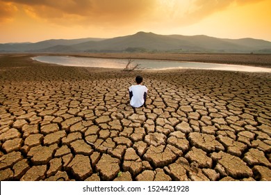 Climate change and global warming concept. Children sitting on drying lake with the sky turning orange by an pollution from industrial or city.
