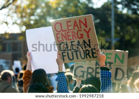 Climate change protest in Melbourne Australia with people holding banners, focus on sign saying clean energy clean future. Global warming and protecting the environment concept. 