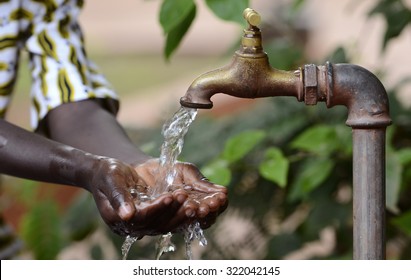 Climate Change Symbol: Handful Of Water Scarsity For Africa Symbol. Hand Of An African Black Boy With Water Pouring From A Tap. 