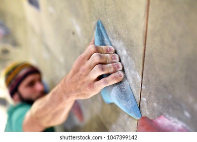 climber bouldering in a sports hall - holding on to the handle of an artificial rock wall  - Shutterstock ID 1047399142