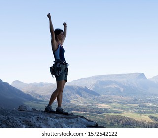 A climber celebrating reaching the top - Shutterstock ID 1572542122