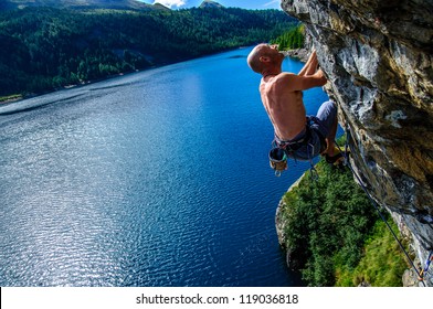 Climber climbing a rock wall above Lake Devero, Northern Italy
