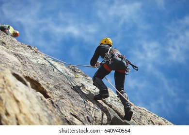 Climber climbs on the rock wall against a blue sky. Climbing gear. Climbing equipment.