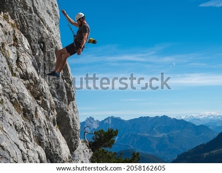 climber decending steep wall with view of the austrian and bavarian alps on a sunny day 