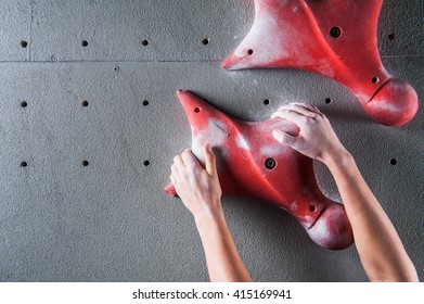 Climber hands holding artificial boulder in climbing gym
