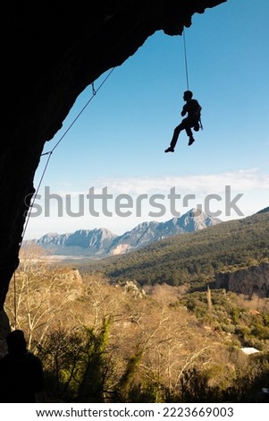 the climber hangs on a rope, the athlete has overcome a difficult climbing route in a cave and descends, climbing belaying, a rock in the form of an arch