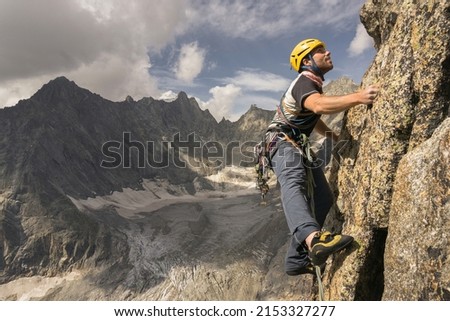 Climber having fun on a rock face on the italian side of Mont Blanc massif in the Alps with glaciers in background