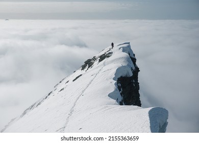 Climber on the final steps of the ascent of a snowy summit of a mountain in the Alps
