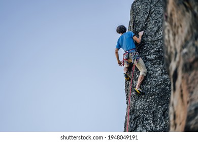 A climber on a steep rock. Rock climbing, extreme adrenaline sport climbing. Ascending a rock wall to the top.