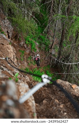 Climber on a Via Ferrata Fixed Rope Climbing Rout decending in a forest environment