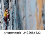 Climber overcomes challenging climbing route. A girl climbs a rock. Woman engaged in extreme sport. Extreme hobby.
