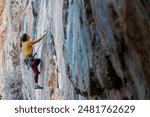 Climber overcomes challenging climbing route. A girl climbs a rock. Woman engaged in extreme sport. Extreme hobby.
