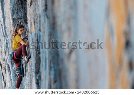 Climber overcomes challenging climbing route. A girl climbs a rock. Woman engaged in extreme sport. Extreme hobby.
