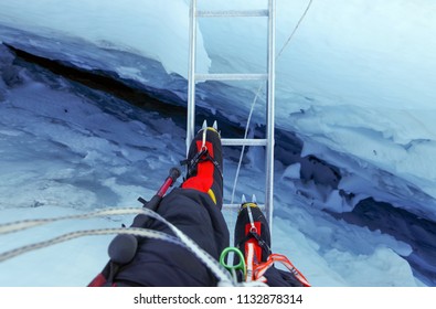 Climber Passes A Crack In The Glacier On The Ladder On The Way To Mount Everest, Himalayas, Nepal