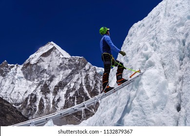 Climber Passes A Crack In The Glacier On The Ladder On The Way To Mount Everest, Himalayas, Nepal