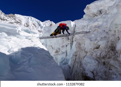 Climber Passes A Crack In The Glacier On The Ladder On The Way To Mount Everest, Himalayas, Nepal