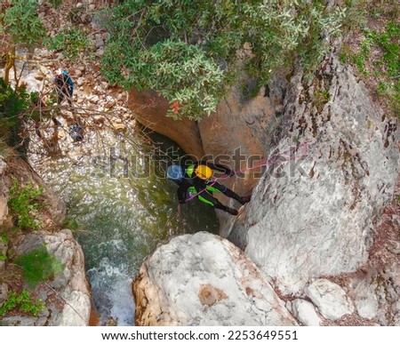 Climber rappelling down a waterfall. Canyoning descent of the waterfall with climbing equipment. Zenith aerial view. Granada. Andalusia. Spain.