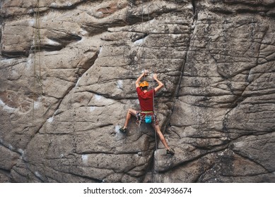 climber with safety rope is climb by vertical sandstone rock by well-trodden route orientate by rubbed stains