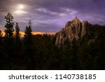 Climber standing on rocky formation top in Black Hills National Park, with a gorgeous landscape view of a sunset 