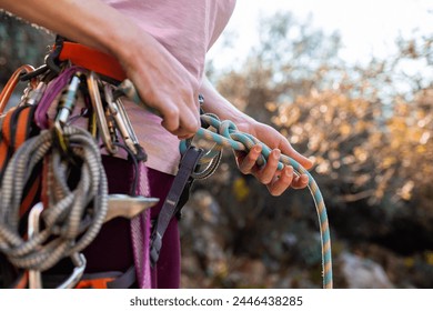 climber tying a knot before climbing. Close-up of a rock climber in harness and climbing equipment outdoors. Alpinism and rock climbing - Powered by Shutterstock