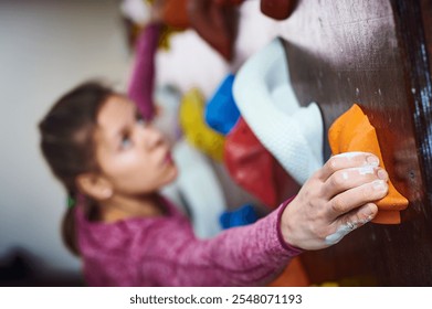 Climber using vibrant holds on indoor climbing wall during training session in gym - Powered by Shutterstock