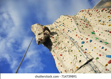 Climber In The Vertical Outside Climbing Wall Of A Climbing Gym At The Surmounting Of An Overhanging Artificial Rock