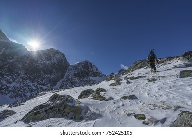 Climbers Ascending A Snowe Ridge To The Summit Of A High Peak. Blue Sky, Beautiful Clouds And Winter Mountians Around. Winter Hiking Adventure.